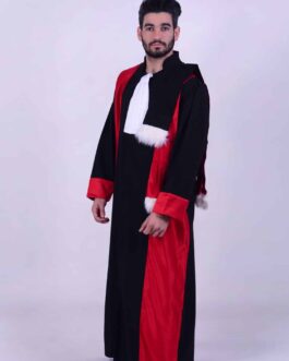 Un homme barbu aux cheveux courts porte la tenue doctorale de cérémonie, qui se compose d'une robe noire avec des touches de rouge et une bordure en fourrure blanche. Il se tient debout sur un fond uni et clair, regardant directement la caméra. La robe a une apparence formelle renforcée par son col blanc.