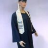 Un mannequin de Toge Standard est vêtu d'une robe de remise de diplôme bleu foncé et d'une casquette avec un pompon blanc. Le mannequin porte également une étole blanche ornée de texte et de logos bleus, représentant probablement un programme ou une institution universitaire. Le fond est uni et de couleur claire.