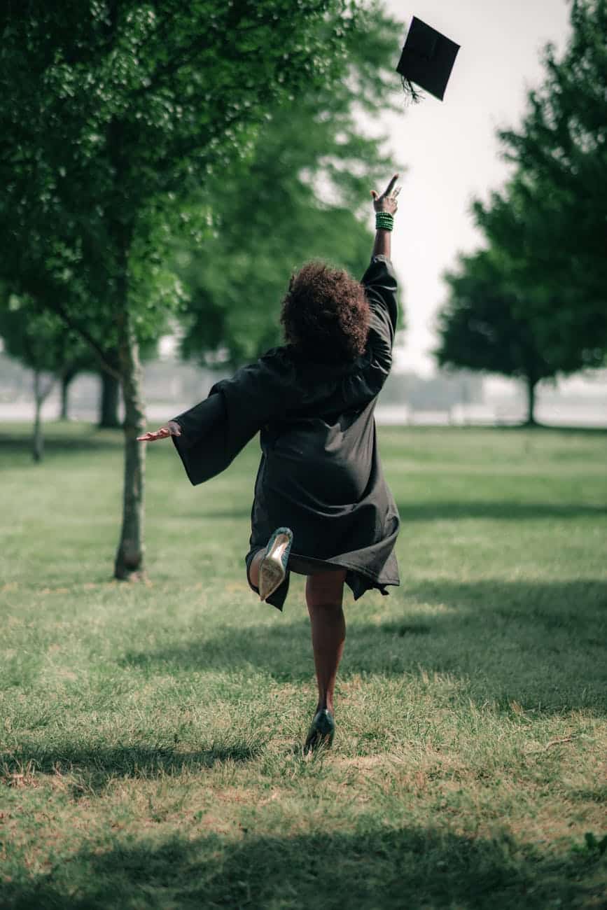 woman in a graduation gown throwing her hat up in the air